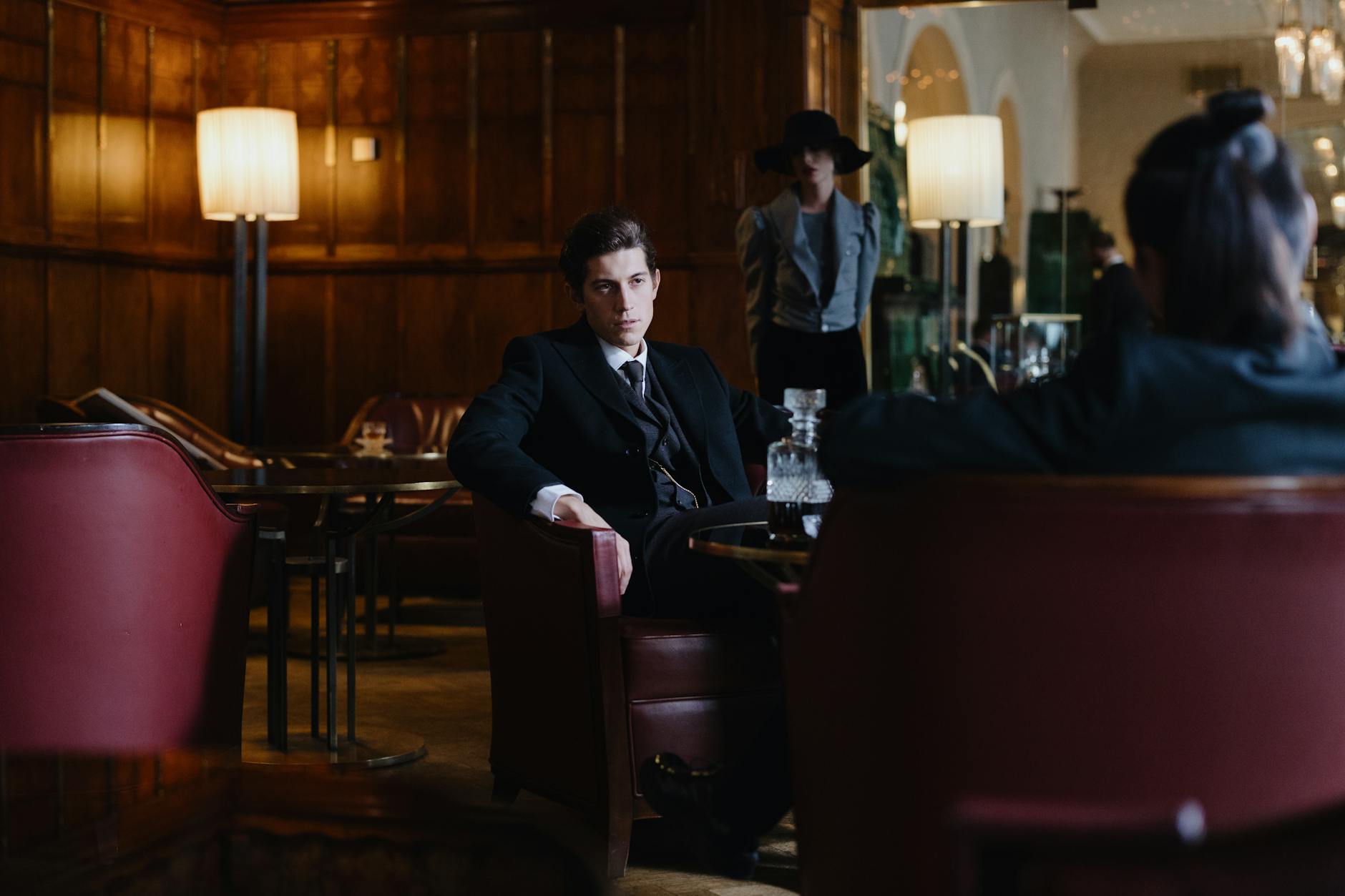 a man in black suit sitting on a leather chair