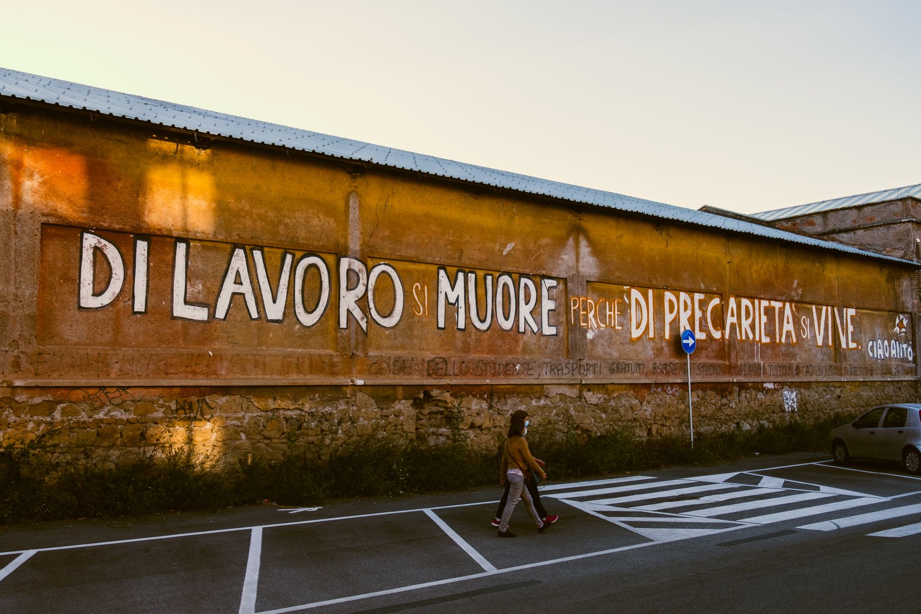 anonymous citizens strolling on road against building with inscription